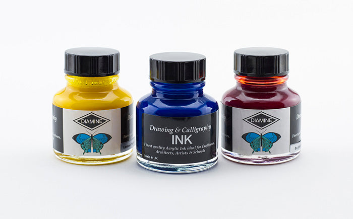 Three glass 30ml bottles of Diamine drawing & calligraphy ink in colours Lemon Yellow, Ultramarine & English Red on a white background.
