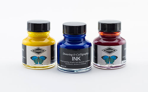 Three glass 30ml bottles of Diamine drawing & calligraphy ink in colours Lemon Yellow, Ultramarine & English Red on a white background.